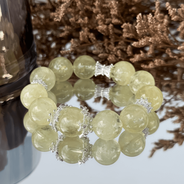 Yellow Azeztulite crystal bead bracelet with silver details on reflective surface