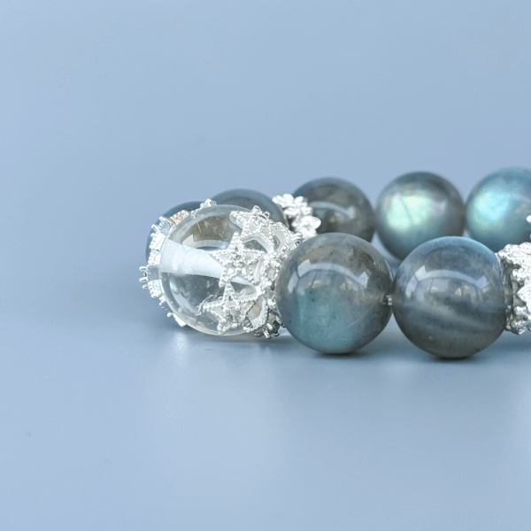 Gray Moonstone crystal bead bracelet with clear center on a blue background.