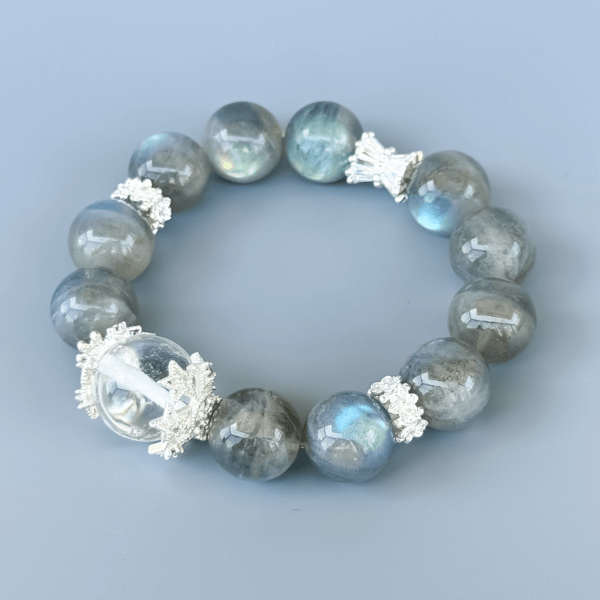 Gray Moonstone crystal bead bracelet with clear center on a blue background.