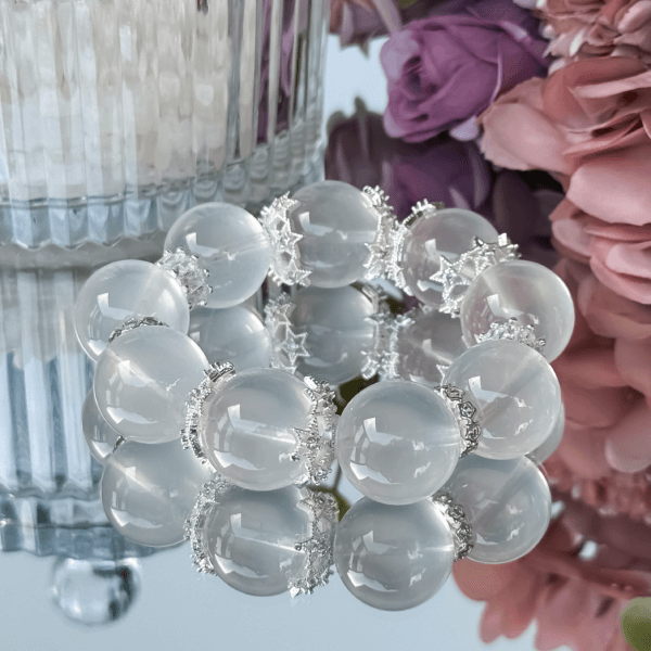 Milky White Crystal Bead Bracelet with Silver Accents on a Reflective Surface