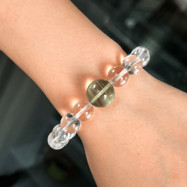 Clear Quartz crystal bracelet with a green bead worn on wrist