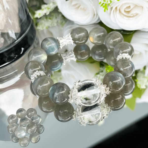 Gray Moonstone crystal bead bracelet with clear center displayed with white roses.