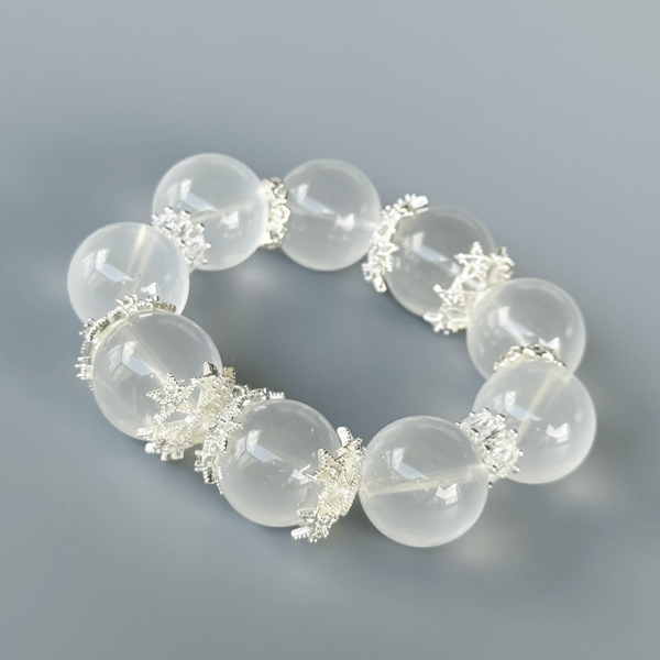 Milky White Crystal Bead Bracelet with Silver Details on a Plain Background
