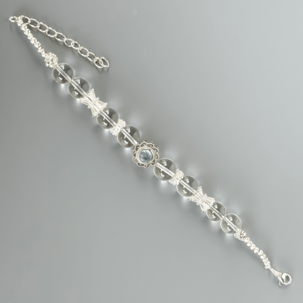 Clear Quartz Bracelet with Floral Silver Centerpiece on Grey Background