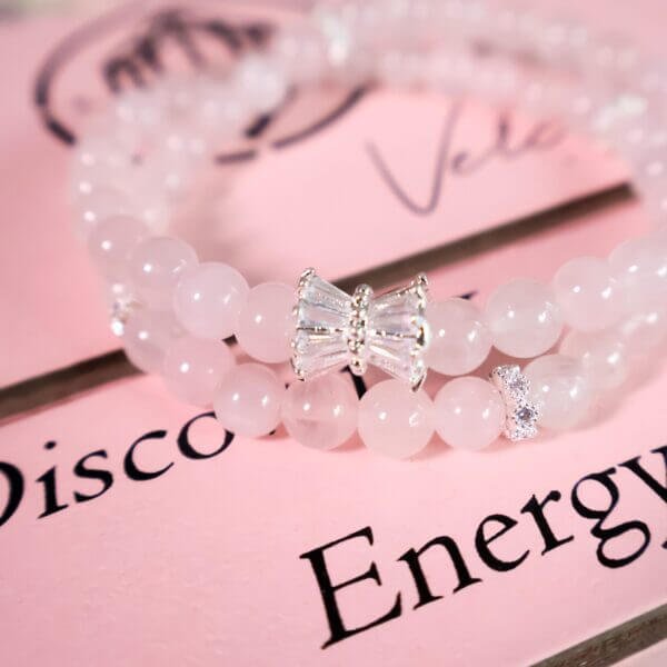 Close-up of rose quartz bracelet with bow-shaped charm