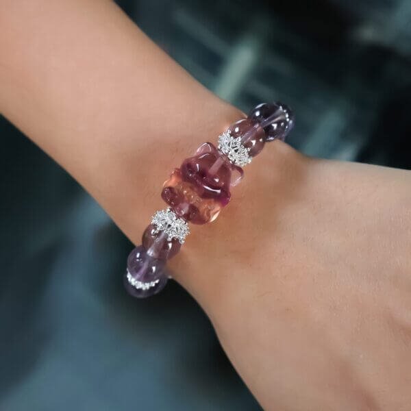 Purple crystal bracelet with silver accents and red charm on pink packaging.