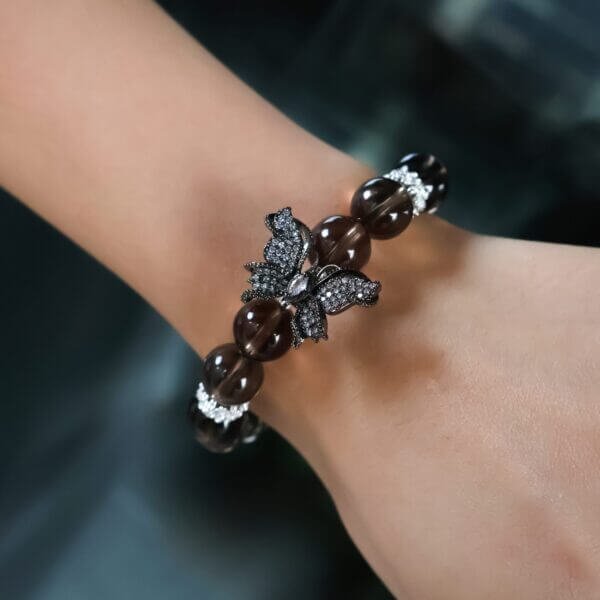 Smoky quartz bracelet with butterfly charm on wrist