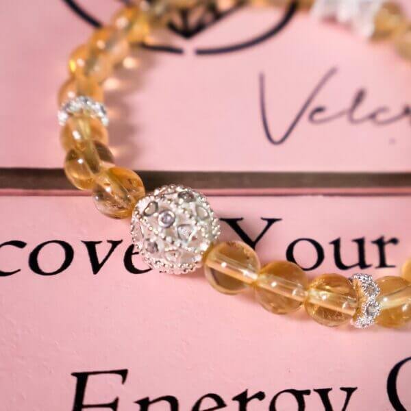 Close-up of yellow quartz bracelet with silver accents on pink background