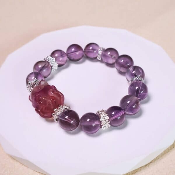Purple amethyst bracelet displayed on a reflective surface with floral decor.