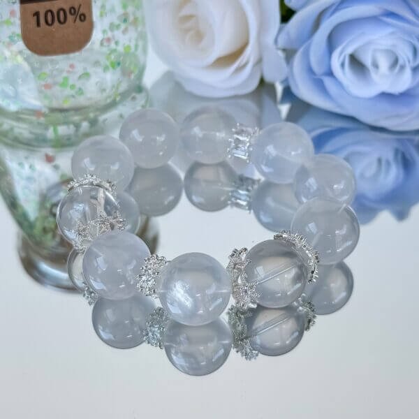 Milk white crystal bead bracelet with silver accents on reflective surface