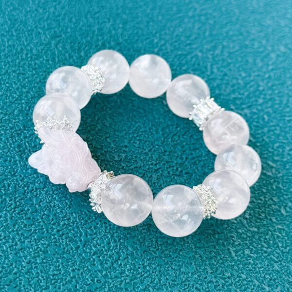 Handmade rose quartz crystal bracelet with carved bead and silver accents