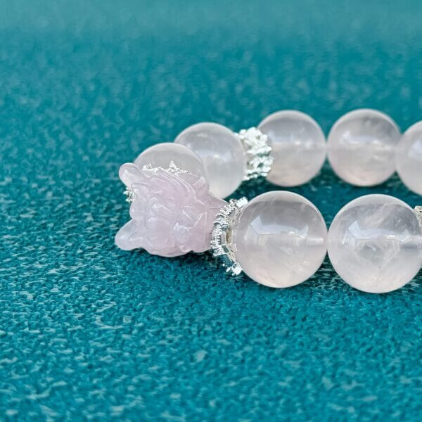 Handmade rose quartz crystal bracelet with carved bead and silver accents