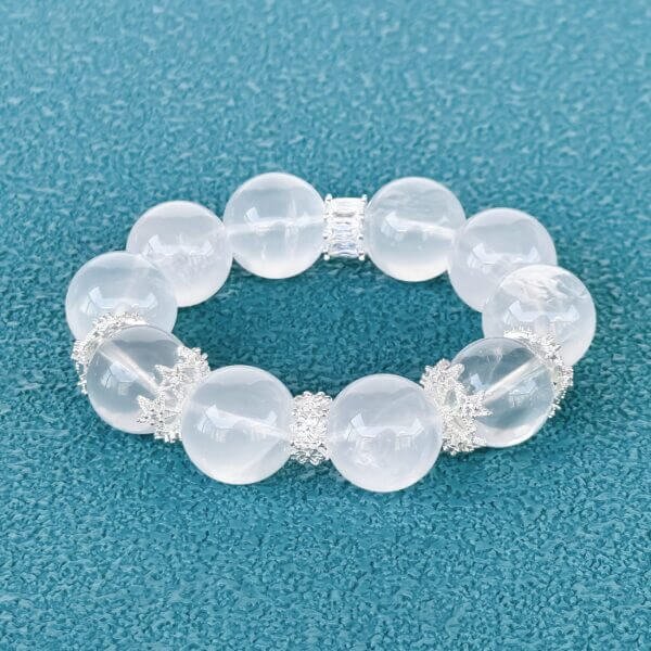 Milk white crystal bead bracelet with silver accents on teal background