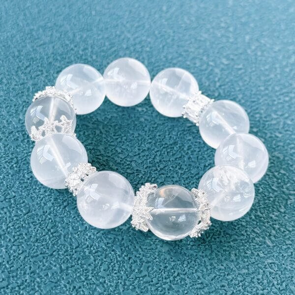 Milk white crystal bead bracelet with silver accents on teal background
