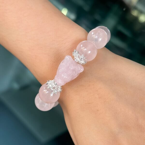 Rose quartz bracelet with carved central bead, worn on wrist